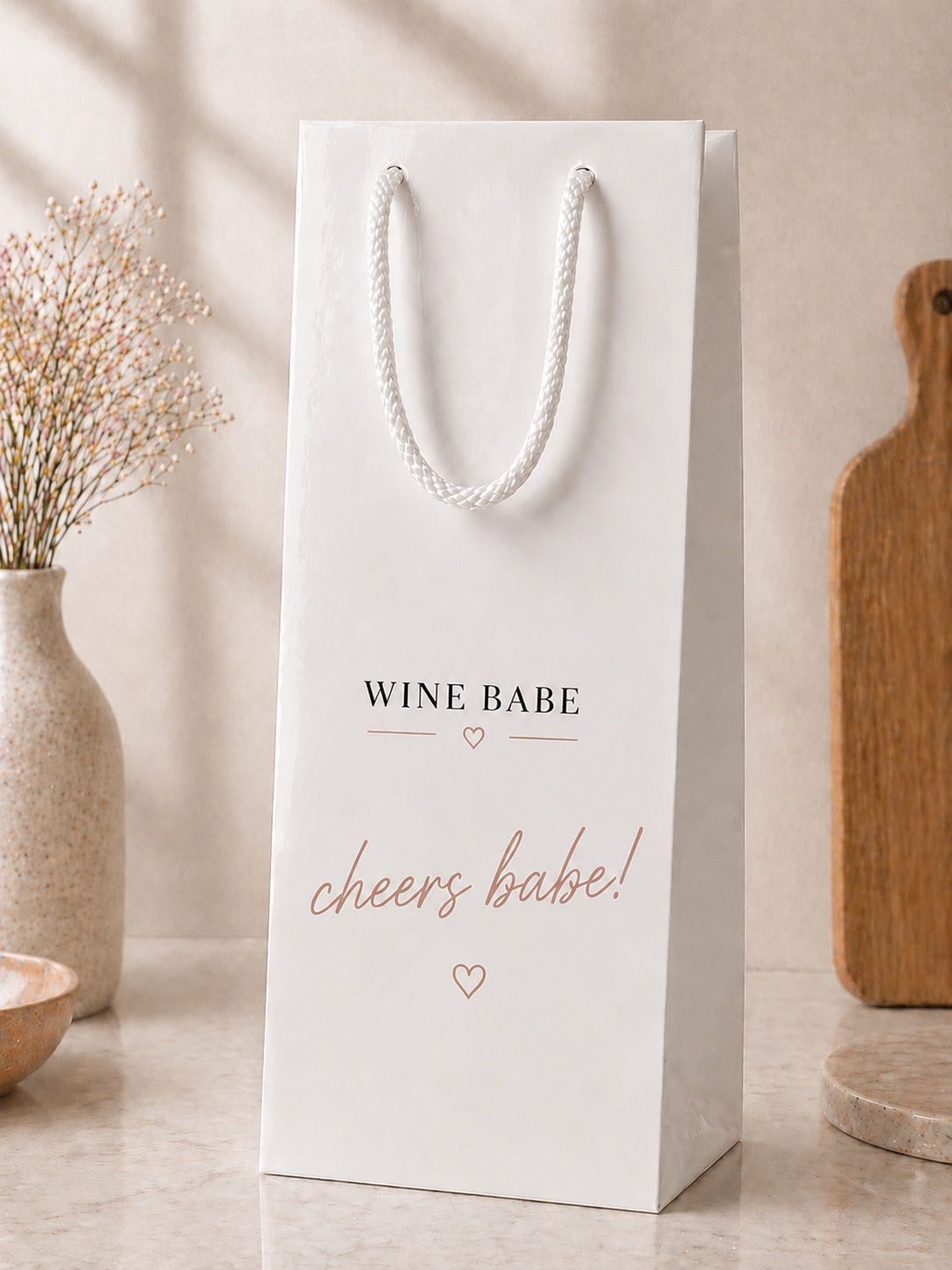 Glossy white Wine Babe gift bag with black serif lockup and cheers babe! in dusty pink script